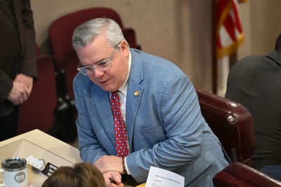 A man in a light blue suit and red tie