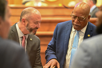 Two men in suits laughing.