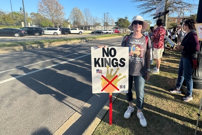 A woman holding a "No Kings" sign