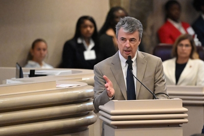 A man in a tan suit and blue tie