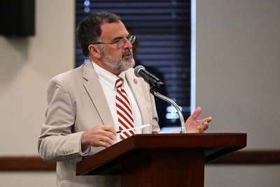 A person in a light jacket and red and white striped tie