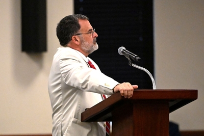 A man in a white suit at a lectern