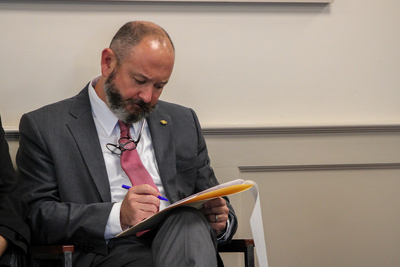A man in a grey suit sitting in a chair annotating legislation.