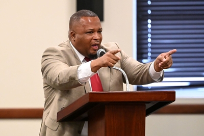 A man in a light suit and red tie pointing his fingers