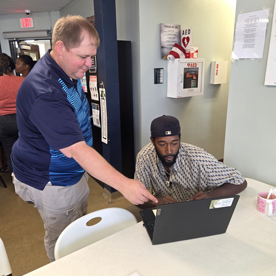 A man pointing to a screen with another man watching