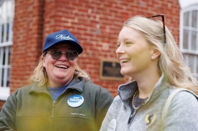 Thacker and Valentine laugh together against a brick building backdrop.