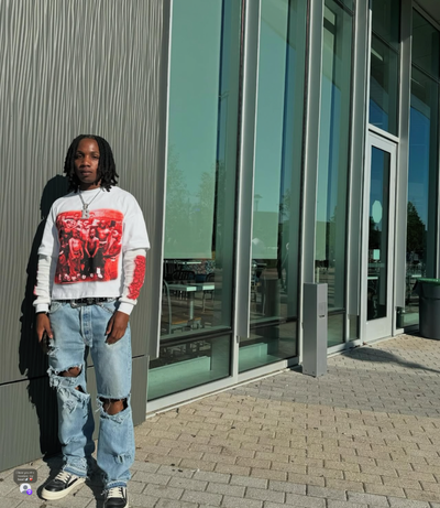 A photo of Muhssia King standing in the sun next to a building.