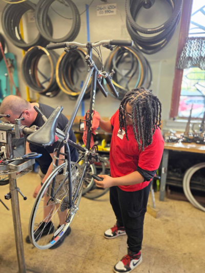 A person fixes a bike elevated in a bike stand.
