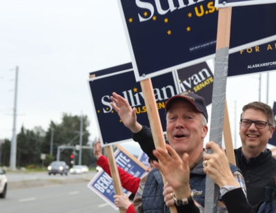 U.S. Sen. Dan Sullivan, center, and Nick Begich III wave signs at an Anchorage intersection in August. (Nathaniel Herz/Anchorage Press)
