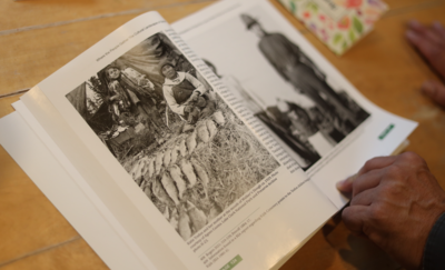 Bill Hill examines a photo of his grandmother, Katie Trefon, at left, and great grandmother, Mary Ann Trefon, from around 1929 in a book at a cousin's house in Port Alsworth. (Nathaniel Herz/Anchorage Press)