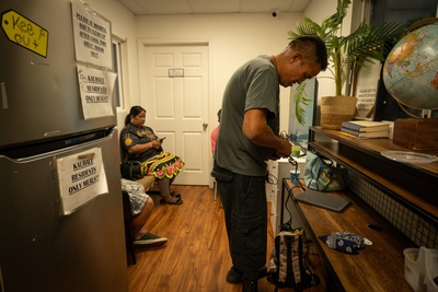 18:50 Kimo Baqui-Manuwai (cq) charges a device as Jacie Hartman (cq) watches television on the grounds of Ho'okahi Leo Kauhale near the Kalihi Transit Center. The kauhale provides facilities to shower, launder clothes and electricity to residents and drop-in clients.