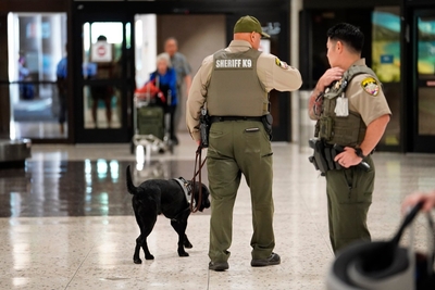 Honolulu Sheriff deputies and K9 patrol the Terminal 1 baggage claim area Monday, Feb. 24, 2025, at Daniel K. Inouye International Airport in Honolulu. (Kevin Fujii/Civil Beat/2025)