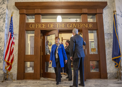 Idaho Gov. Brad Little (right) holds the door for the delegation of legislators, including Senate Minority Leader Melissa Wintrow, D-Boise, selected to escort him to the House chamber to give his annual State of the State address