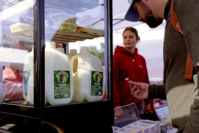 Jenna Evans, of Evans Farmstead Cheese, sells dairy products to customers at a farmers market in Boise