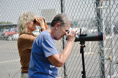 Maureen Newton, left, and Karen Stroder, use binoculars and a telescope to look through the fence at an immigration and customs enforcement flight operating out of the Magic Valley Regional Airport.
