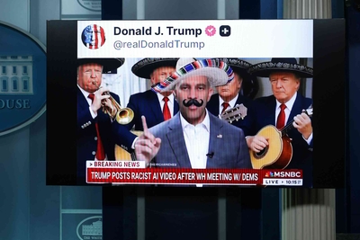 A screen in a press briefing room shows a social media video of a man in a sombrero and fake mustache, flanked by mariachi musicians, above a cable news banner.