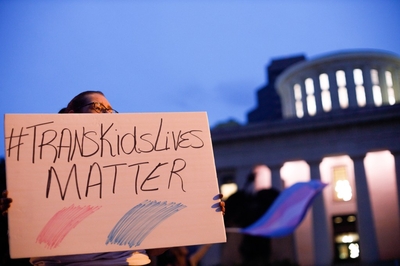 Transgender rights advocate holds a sign outside the Ohio Statehouse during a rally.