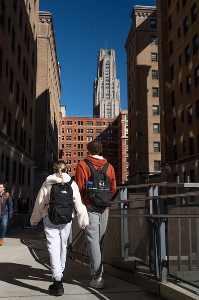 People on the University of Pittsburgh’s Oakland campus, with the Cathedral of Learning towering in the background on Feb. 6, 2024. (Photo by Stephanie Strasburg/Pittsburgh’s Public Source)