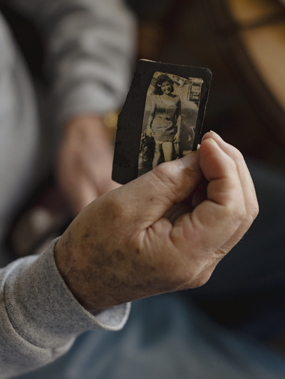 Gabe Betancourt holds an old photograph of his wife, Nellie, that he keeps in his wallet. “I carry her with me everywhere I go,” he says. (Photo by Adria Malcolm for KFF Health News)