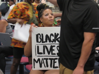 A Black Lives Matter protester attending a Wauwatosa City Council meeting. Protestes had been marching to get officer Joseph Mensah fired for killing three people over just five years. (Photo by Isiah Holmes)