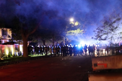 A line of officers in riot and militarized gear block a street in Wauwatosa during the October curfew. Tear gas was still thick in the air. (Photo by Isiah Holmes)