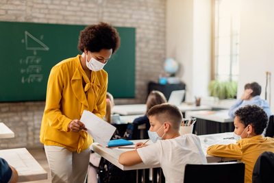 Teacher talking with seated pupils in a math class, students look older elementary school age