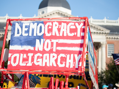 A sign reading "Democracy Not Oligarchy" in front of the State House in Annapolis