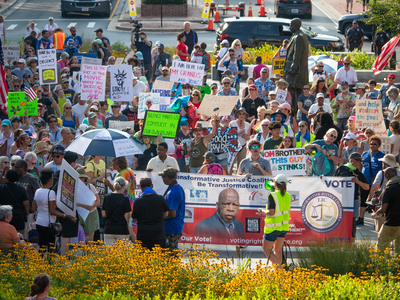 Protestors hold signs during the “Good Trouble Lives On” rally in Annapolis