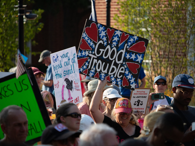A person carries a "Good Trouble" sign