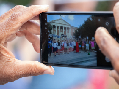 A person takes a photo of demonstrators holding signs