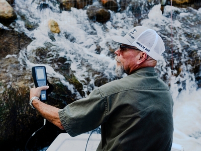 Chris Cuellar holds a probe that tests for total dissolved solids next to the discharge from water wells on the Nueces River in Nueces County.