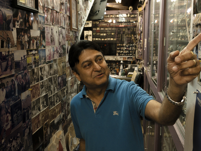 Luvi Samtani points to a family photograph inside his watch store in downtown Laredo on April 9, 2026. He says customer traffic has declined over the past year.