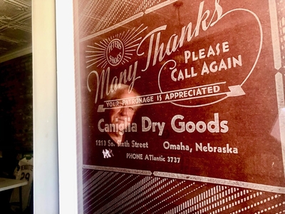 The front door of the family museum is decorated with a print of the paper used to wrap goods purchased at the Caniglia Dry Goods store decades ago. (Cindy Gonzalez/Nebraska Examiner)