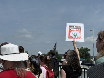 A demonstrator holds up a sign as protesters march back across the Veterans Memorial Bridge as part of the No Kings protest in Little Rock on Saturday, June 14, 2025. (Ainsley Platt/Arkansas Advocate)