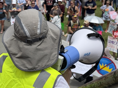 A protest organizer looks down at the remaining crowd during the rally that followed a march across Veterans Memorial Bridge as part of the No Kings protest in Little Rock on Saturday, June 14, 2025.