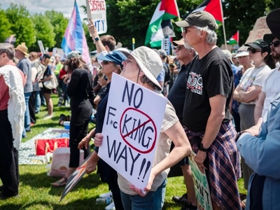A group of people at a protest; a person in the foreground holds a sign that reads "NO F**KING WAY!!" with the obscenity partially censored.