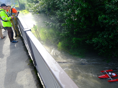U.S. Geological Survey (USGS) crews use a device to measure depth, speed of water and amount of water in the flooded Mendenhall River, on Aug 13, 2025 (Photo by Corinne Smith/Alaska Beacon)