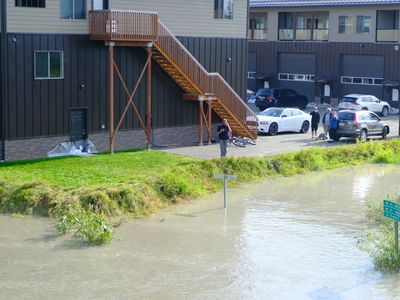 Onlookers view the flooded Mendenhall River on Aug 13, 2025 (Photo by Corinne Smith/Alaska Beacon)