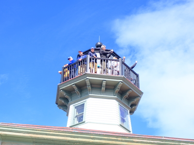 Members of the Eldred Rock Lighthouse Preservation Association board of directors celebrate and cheer following the opening ceremony for the lighthouse on May 30, 2026. (Photo by Corinne Smith/Alaska Beacon)
