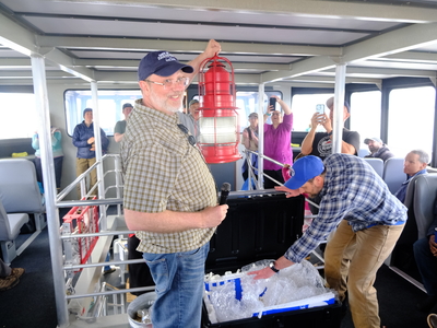 Doug Adamson, the great-grandson of the first lighthouse keeper at Eldred Rock Lighthouse, Nils P. Adamson, presents to a post lantern owned by his great-grandfather and kept by the family as a gift to the lighthouse's future maritime museum on May 30, 2026. (Photo by Corinne Smith/Alaska Beacon)