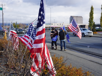No Kings Day participants wave flags and signs along Northern Lights Boulevard in Midtown Anchorage on Oct. 19, 2026. (Photo by Yereth Rosen/Alaska Beacon)