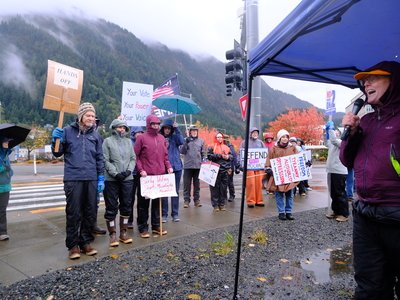 Anjuli Grantham, an organizer with Juneau for Democracy, speaks to a crowd gathered for a nationwide No Kings day of action on Oct. 17, 2026 and urges Alaskans to vote early. (Photo by Corinne Smith/Alaska Beacon)