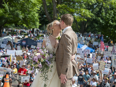 Advocates Melissa Stiehler and Davis Hammet kiss on the Statehouse steps during the June 14, 2025, "No Kings" rally Saturday in Topeka