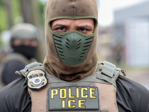 In this photo, a U.S. Immigration and Customs Enforcement agent watches a crowd of protesters at Delaney Hall in Newark, N.J., on May 25, 2026. (Photo by Ben Ackman/New Jersey Monitor)