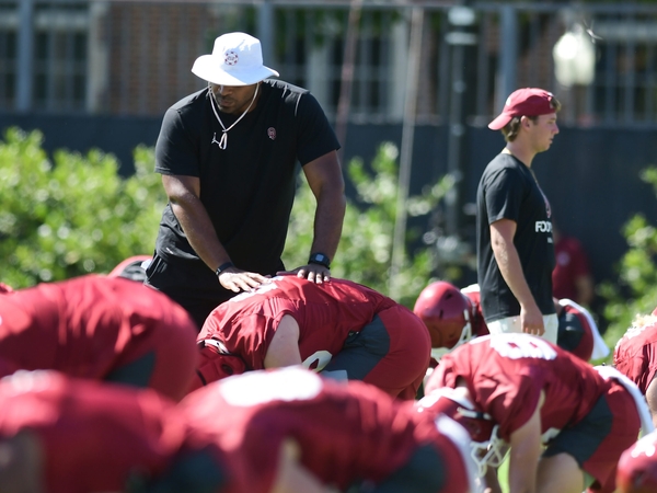 University of Oklahoma football coach helps players stretch during practice on Aug. 4, 2023. (Photo by Kyle Phillips/For Oklahoma Voice)