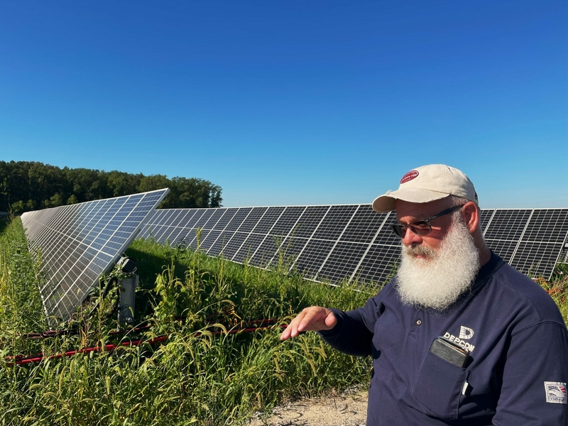 Tracy Anthony, site lead for Depcom, an Entergy contractor, stands in front of a row of solar panels at Entergy Arkansas’ 100 megawatt solar and storage plant in Searcy, Arkansas. Anthony said renewable power, coupled with battery storage, will “play an important part in power generation in the near future.” (Robert Zullo/ States Newsroom)