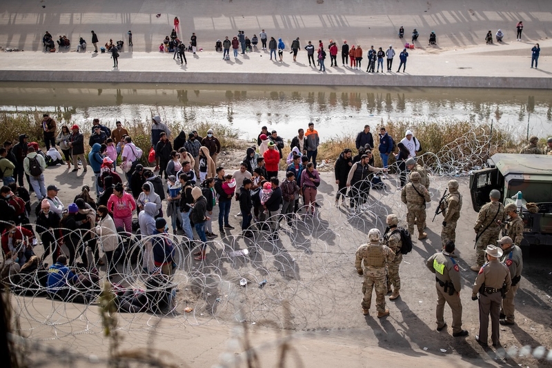 Barbwire separates migrants and Texas troops and law enforcement on the banks of the Rio Grande on Tuesday, Dec. 20, 2022, in El Paso. (Photo by Ivan Pierre Aguirre for The Texas Tribune)