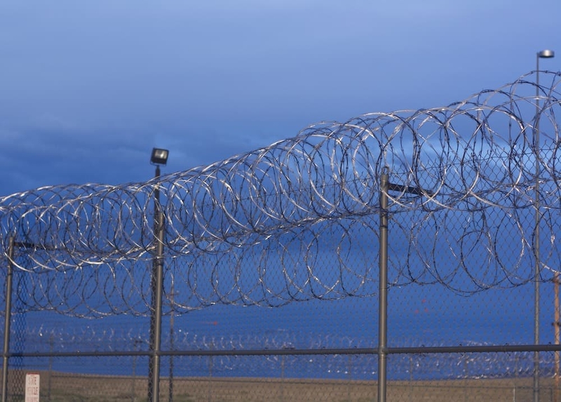 Christopher Hicks is serving his three consecutive life sentences at the Wyoming State Penitentiary in Rawlins. Pictured here is a section of barbed wire fence surrounding one section of that facility. (Andrew Graham/WyoFile)