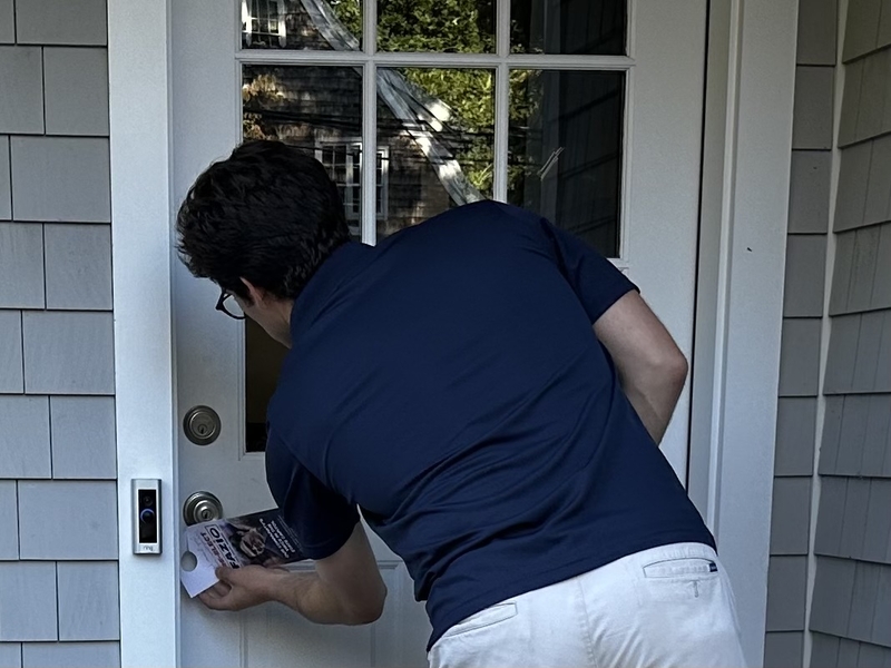 State legislative campaigns still are waged at the doors. Ryan Fazio places a hang tag on the door of a house where no one answered. Credit: mark pazniokas / ctmirror.org