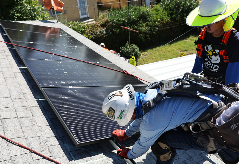 GRID Alternatives employees Sal Miranda (C) and Tony Chang install no-cost solar panels on the rooftop of a low-income household on October 19, 2023 in Pomona, California. GRID Alternatives has installed no-cost solar for over 29,000 low-income households located in underserved communities which are most impacted by pollution, underemployment and climate change. They are the country’s biggest nonprofit clean energy technologies installer and operate in California, mid-Atlantic states and Colorado. (Photo by